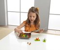 Meisje met oranje top en gele strik leest instructies bij een eekhoornpuzzelspel.