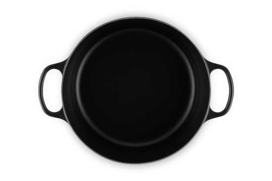 Zijaanzicht van een zwarte Le Creuset braadpan met deksel.