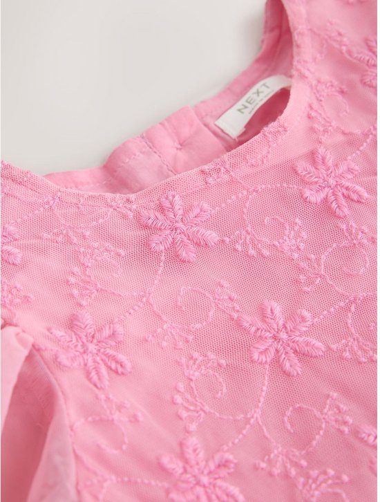 Halslijn van een roze feestjurk met geborduurde bloemen en het "NEXT" merklogo op het label.