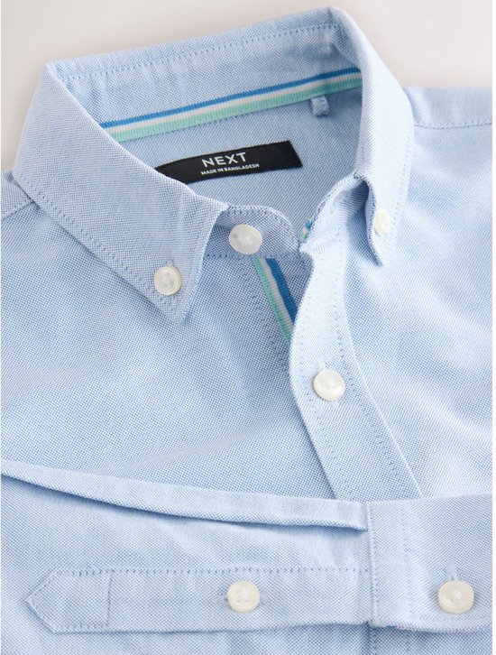 Lichtblauwe katoenen Oxford blouse, met een knoopsluiting en een geborduurd hert-logo op de borst.