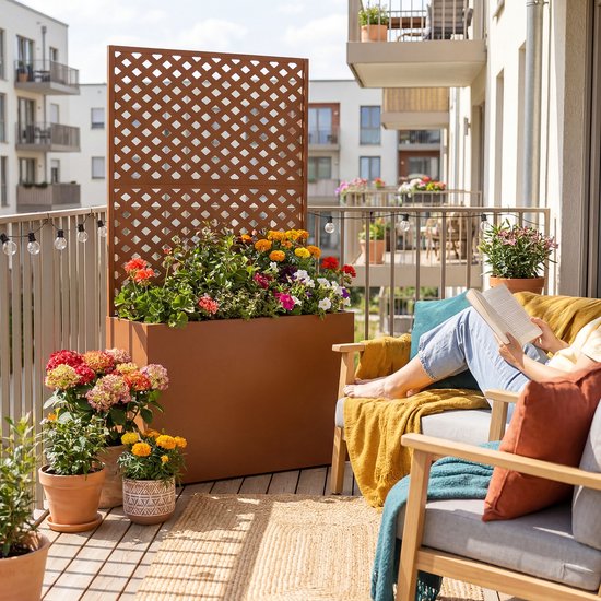 Bruine plantenbak met veelkleurige bloemen op een balkon.