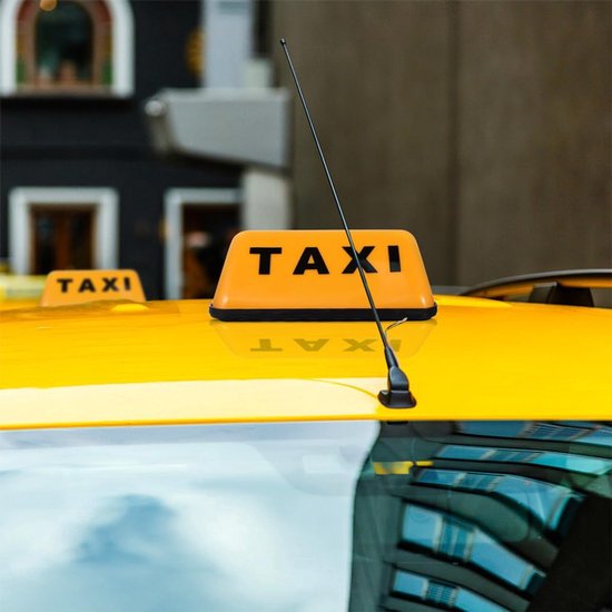 Oranje taxibord met zwarte letters 'TAXI' op een geel taxidakoppervlak, met antenne.