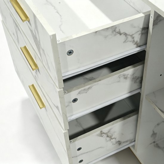 Binnenkant van een wit marmerlook dressoir met gouden handvatten en drie open lades.