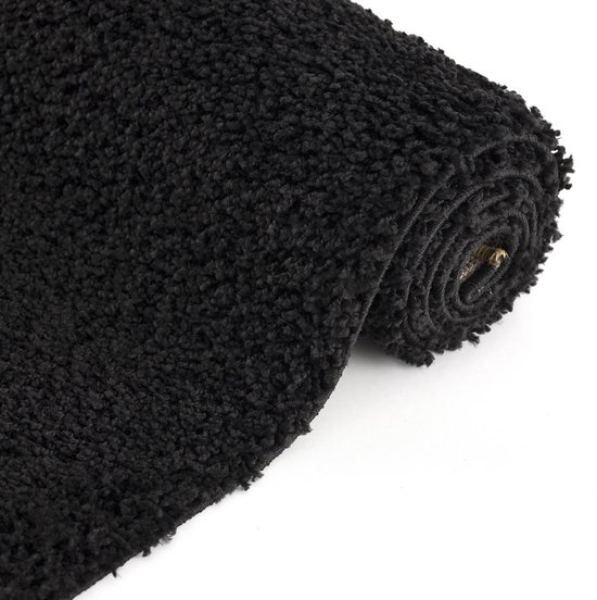 Tapis shaggy noir à poils longs, enroulé. La texture est douce et duveteuse avec un motif uni.