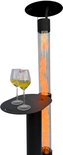 Zwarte terrasverwarmer met tafel, twee glazen witte wijn en vlammen in de glazen cilinder.