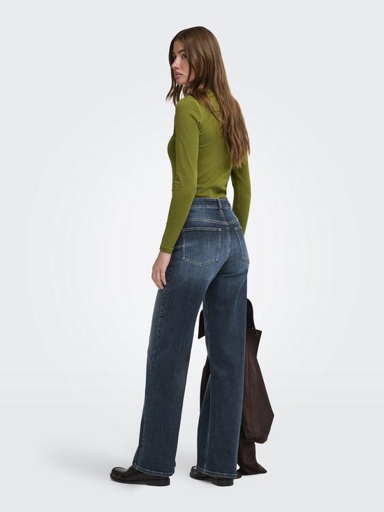 Model van achteren gezien in een olijfgroene coltrui en wijde spijkerbroek met een stonewash-look.