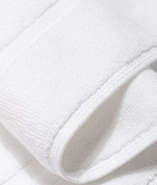 Detail van een witte, zachte badmat met zichtbare textuur.