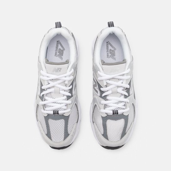 Bovenkant van twee lichtgrijze sneakers met witte veters en grijze accenten.