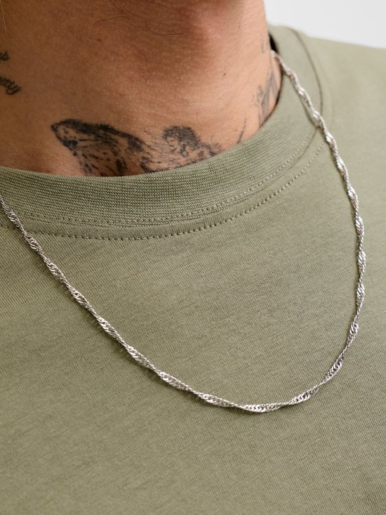 Close-up van een olijfgroen T-shirt met een zilverkleurige ketting.