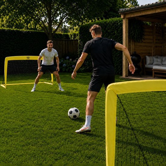 Twee mannen spelen voetbal op een grasveld met twee gele Umbro voetbaldoeltjes.