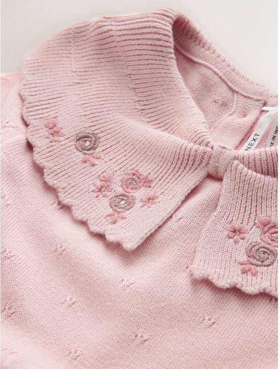 Detail van de roze gebreide kraag met Next-label en geborduurde bloemen.