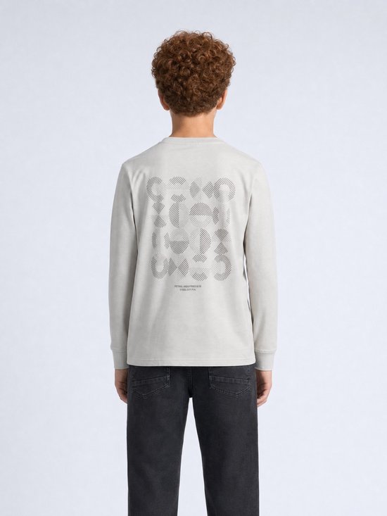 Jongen met krullend rood haar, van achteren gezien, in een lichtgrijze longsleeve met grafische print.