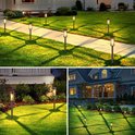 Set van zwarte, cilindervormige solar tuinlampen met filament LED, die warm wit licht uitstralen op een grasveld en langs een pad, zowel overdag als 's nachts.