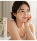 Model met een zachte glimlach houdt haar gezicht vast met haar hand, met een roze tube van Beauty of Joseon Ginseng + Retinol Revive Eye Serum ernaast.