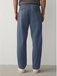 Man staat achterwaarts in blauwe chino broek.