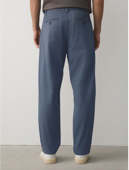 Man staat achterwaarts in blauwe chino broek.