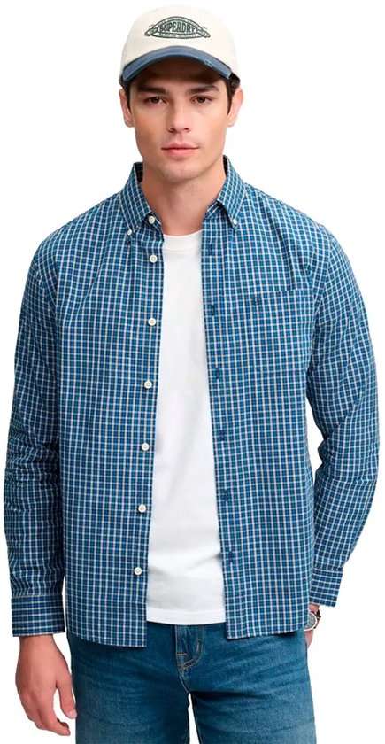 Man met blauw geruit overhemd, witte t-shirt en spijkerbroek. Draagt een pet.