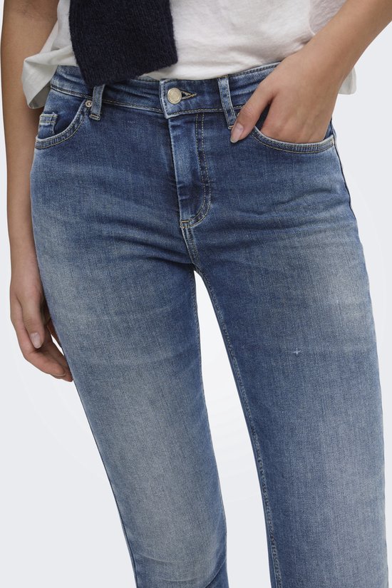 Detail van blauwe skinny jeans met lichte wassing en rafelige zoom.