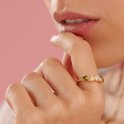 Gouden ring met vijf hartvormige stenen in groen, lichtroze en wit, gedragen door een model.