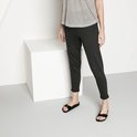 Model draagt zwarte Birkenstock slippers met gesp en een gestreepte top en donkere broek.