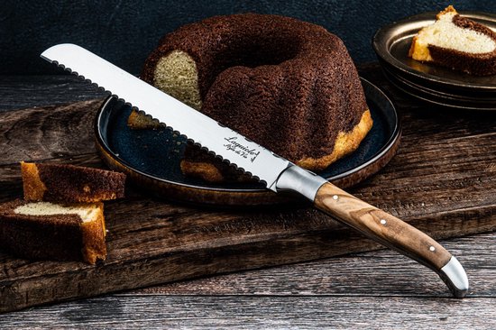 Een marmercake, gesneden, met een broodmes met olijfhouten handvat, op een houten plank.