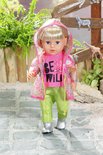 Pop met blond haar, roze T-shirt 'BE WILD', regenjas met luipaardprint, knalgroene broek en zilveren laarsjes.