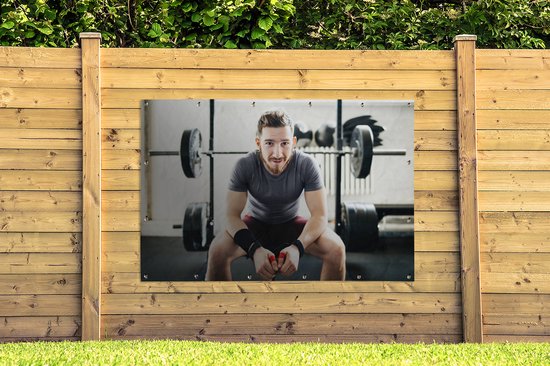 Portrait d'un haltérophile amateur assis sur son banc de musculation Affiche de jardin 180x120 cm - Toile de jardin / Toile d'extérieur / Peintures d'extérieur (décoration de jardin) XXL / Groot format!