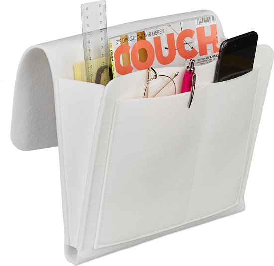 Witte vilten bed- of bankzak met twee voorvakken, waarin tijdschriften, een bril, een pen en een telefoon liggen.