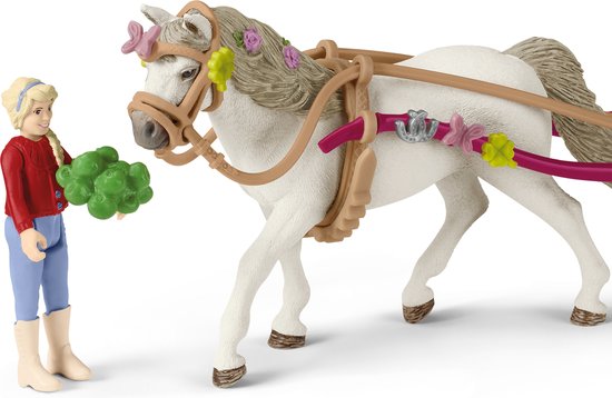 Schleich meisje met rode trui geeft een bosje groen aan een wit paard met bloemen.