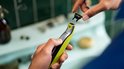 Handen wisselen het mesje van een groene en zwarte Philips OneBlade trimmer.