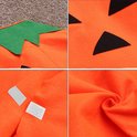 Detailopname van oranje pompoen kostuumstof: groene bladeren, zwart driehoekig gezicht, klittenbandsluitingen en textuur.