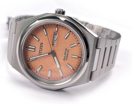 Citizen Eco-Drive horloge van zilverkleurig titanium met perzikkleurige wijzerplaat, in de hand gehouden.