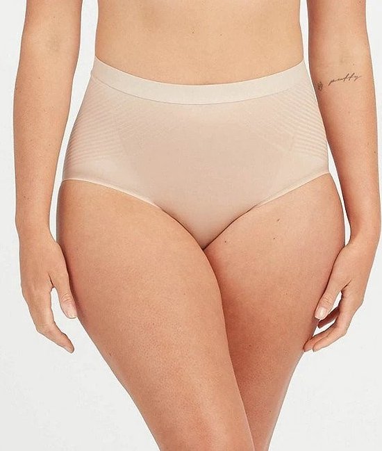 Model in nude shapewear broekje met hoge taille en subtiele patroonlijnen.