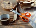Oranje Fiskars schaar tussen rolletjes bruin inpakpapier en bubbeltjesplastic.