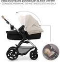 Crème kinderwagen met XL zonnekap en een inset met slapende baby.