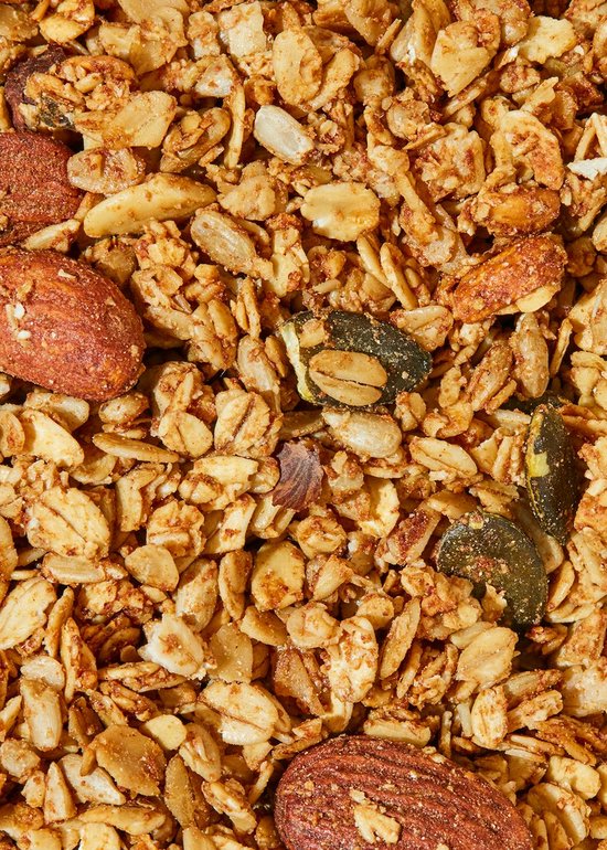Gedetailleerde close-up van knapperige biologische granola met amandelen, pompoenpitten en havermout.