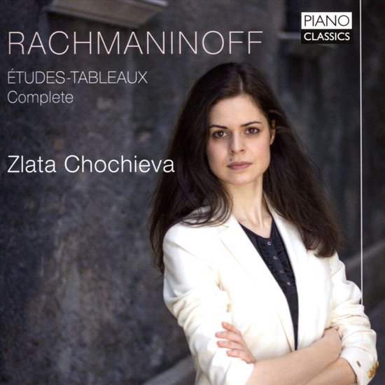 Vrouw met lang bruin haar, gekleed in een wit jasje en zwart topje, staat met gekruiste armen. Titel: Rachmaninoff Études-Tableaux Complete. Pianist: Zlata Chochieva.