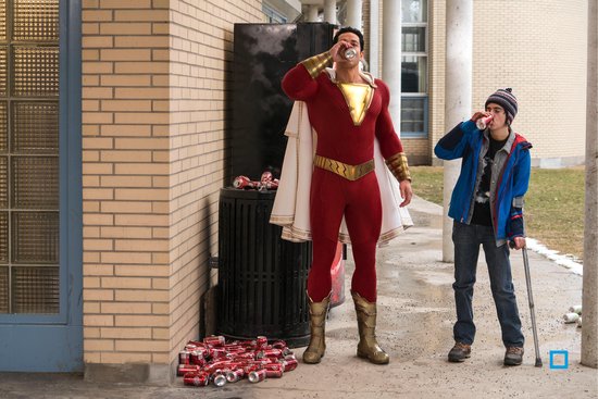 Shazam en een jongen drinken allebei uit blikjes, met een stapel lege blikjes naast een vuilnisbak.