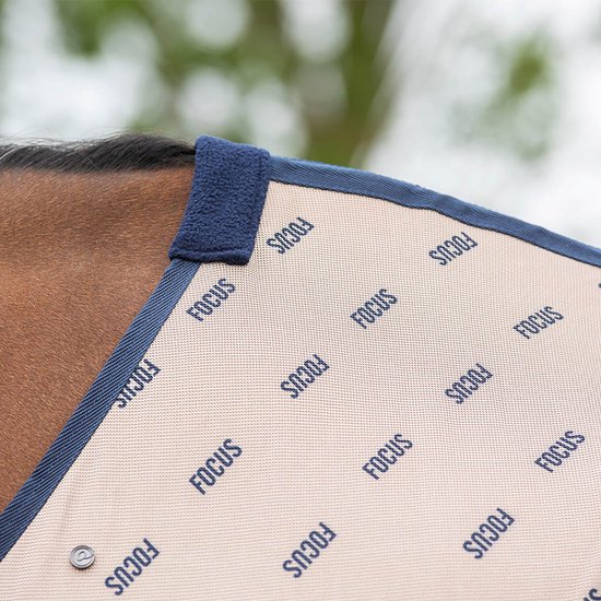 Close-up van de schouder van een paard met beige vliegendeken, navy rand en 'FOCUS' logo.