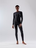 Vrouw draagt een donkergrijs thermoshirt en bijpassende thermobroek. Beide met subtiel logo.