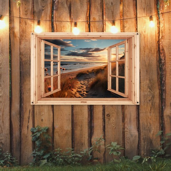 Tuinposter met houten raam, strand met duinen bij zonsondergang, opgehangen aan een houten schutting met lampjes.