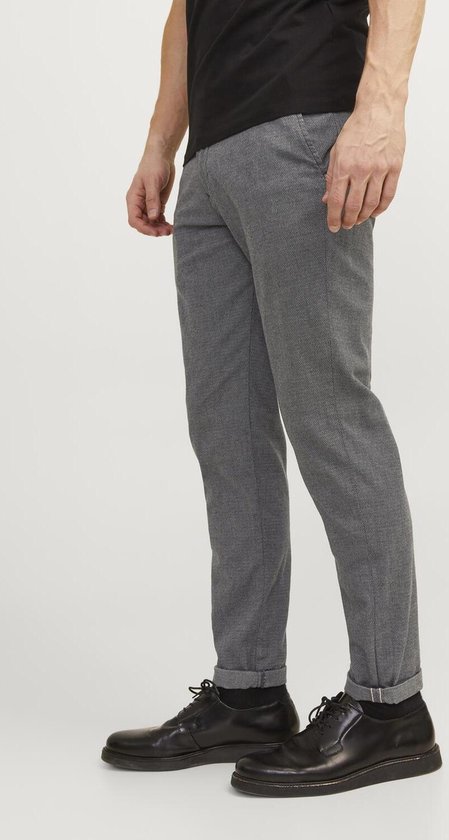 Man in grijze chino, met de pijpen opgerold.