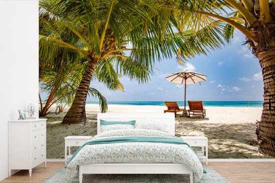 Chaises longues entre les palmiers sur une plage de Bali fotobehang