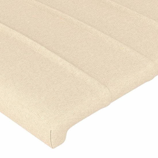 Détail de tissu crème avec coutures verticales sur une tête de lit.