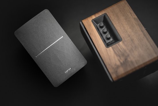 Edifier R1280DB luidsprekers met houten zijkanten en grijze voorkant, liggend op een donkere ondergrond.