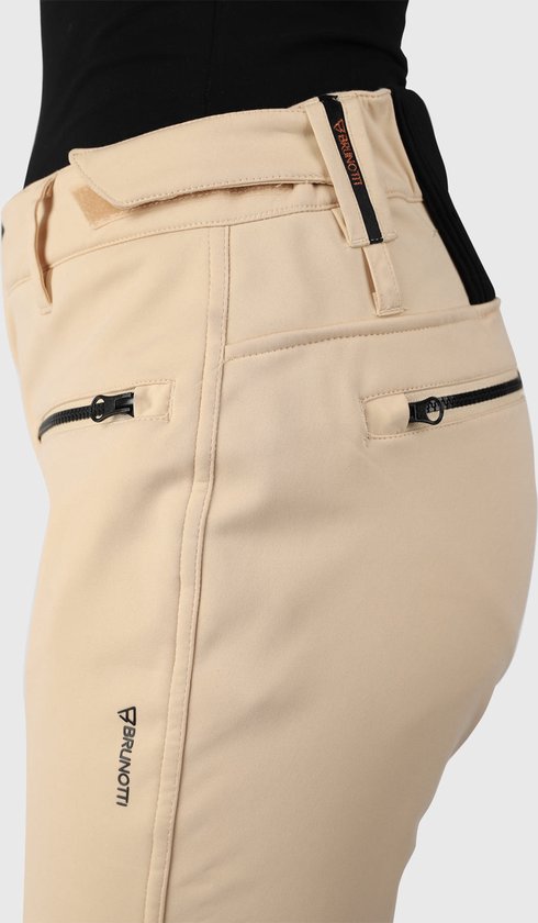 Detail van de zijkant van een beige skibroek met merklogo en ritszakken.