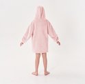 Een kind staat met de rug naar de camera, gekleed in een roze, oversized hoodie met capuchon.