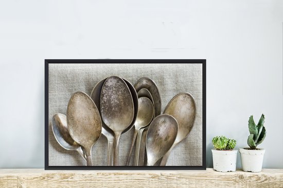 Une collection de cuillères rouillées et antiques de tailles variées. Ces cuillères sont placées sur une toile de lin uniforme 60x40 cm