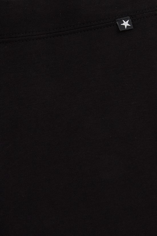 Detail van een zwarte legging met een klein wit sterretje op een zwart label bij de tailleband.