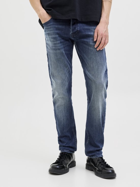 Close-up van de benen van een man in een zwart T-shirt en blauwe jeans.